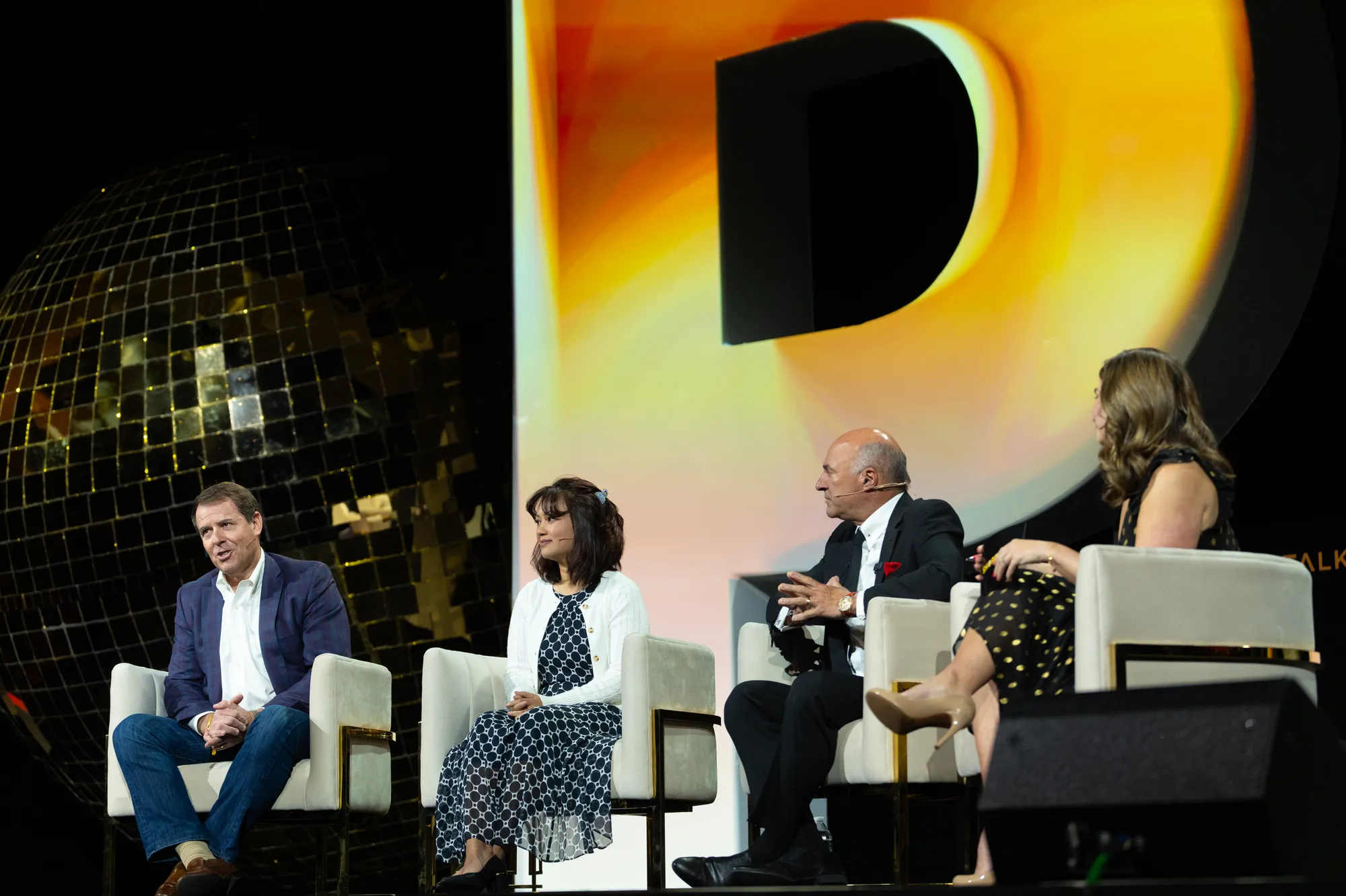 Shoptalk Spring 2025 mainstage: a panel seated in front of the gold mirrored sphere and an illuminated letterform